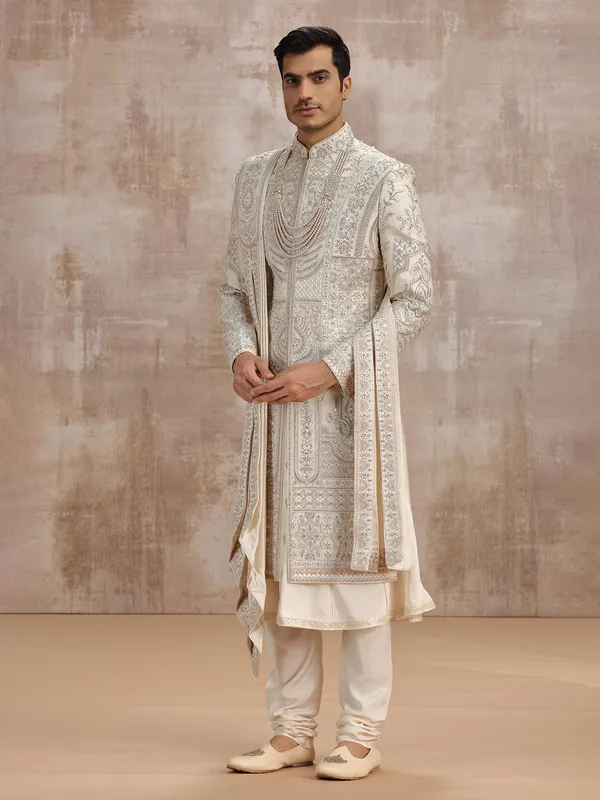 Cream silk peshwai sherwani paired with dupatta