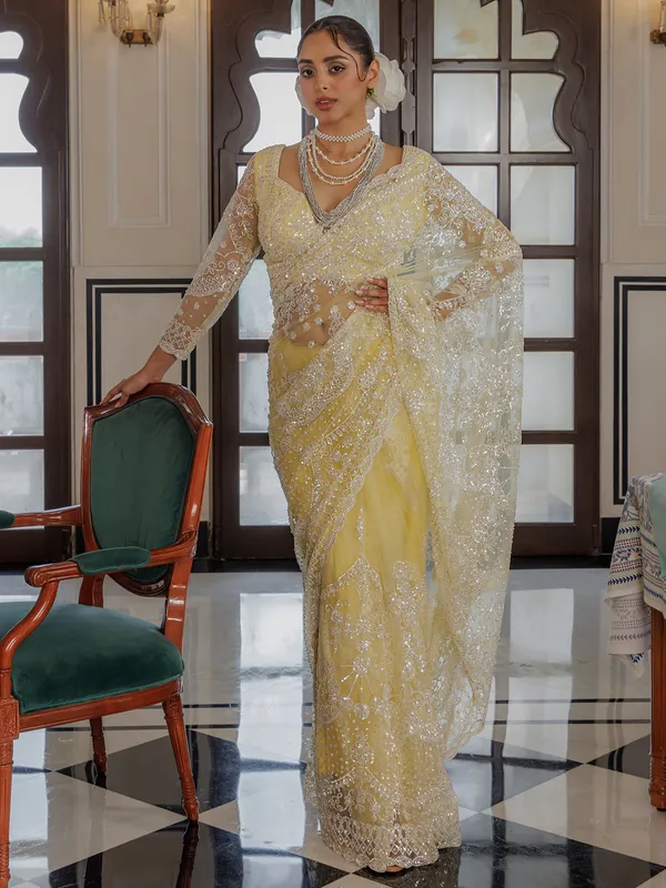 Yellow net saree for rich sequins work